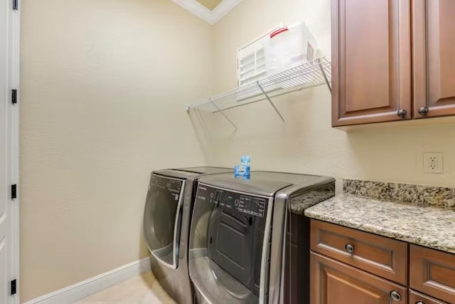 laundry area featuring cabinets, ornamental molding, and washer and clothes dryer