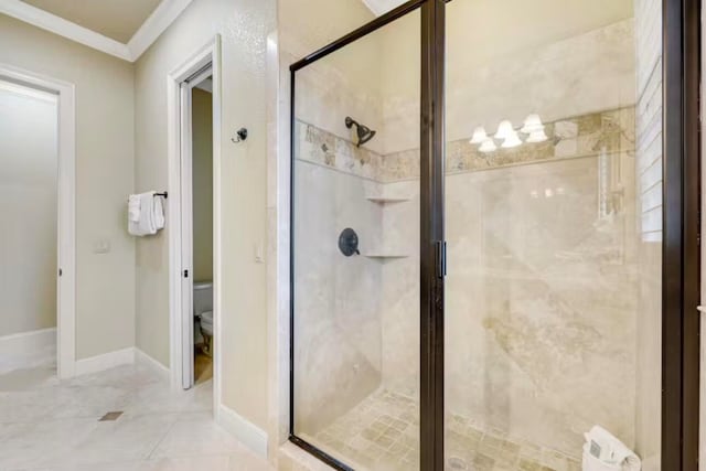 bathroom featuring crown molding, a shower with shower door, and toilet