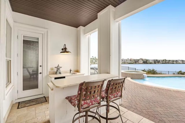 view of patio / terrace with a swimming pool with hot tub, pool water feature, and a water view