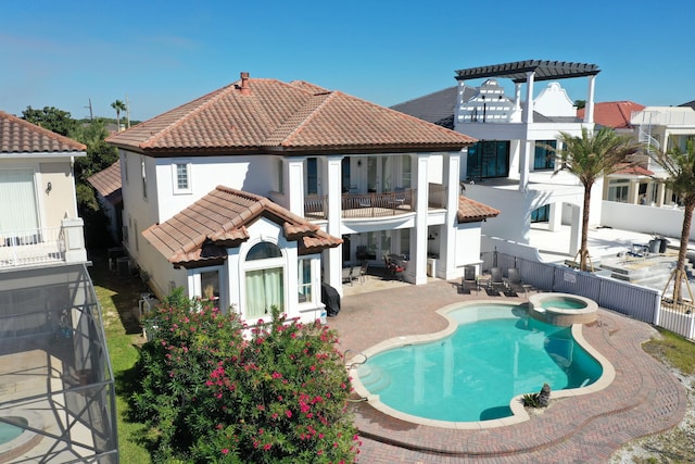 back of property featuring a patio, a balcony, and a swimming pool with hot tub