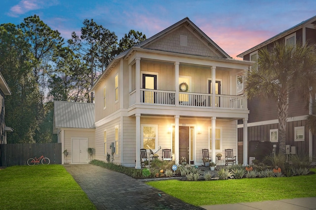 view of front facade with a lawn, a balcony, and a porch