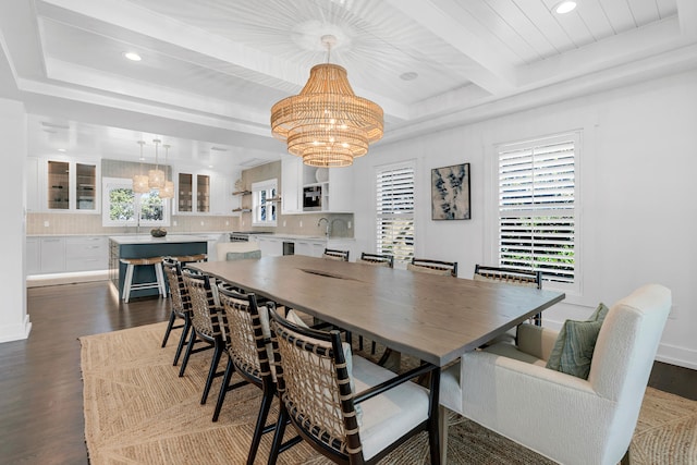 dining space with a raised ceiling, beam ceiling, an inviting chandelier, and dark hardwood / wood-style flooring