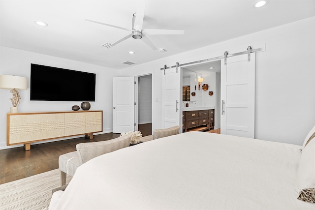 bedroom featuring ensuite bath, ceiling fan, a barn door, and wood-type flooring