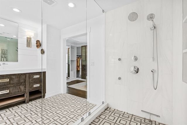 bathroom with tile patterned floors, a tile shower, and vanity