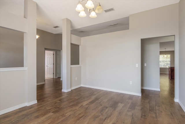 spare room featuring a chandelier and dark wood-type flooring