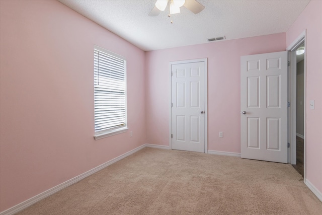 unfurnished bedroom featuring a textured ceiling, light colored carpet, and ceiling fan