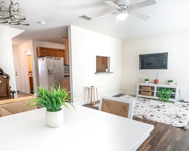 dining space featuring wood-type flooring and ceiling fan with notable chandelier