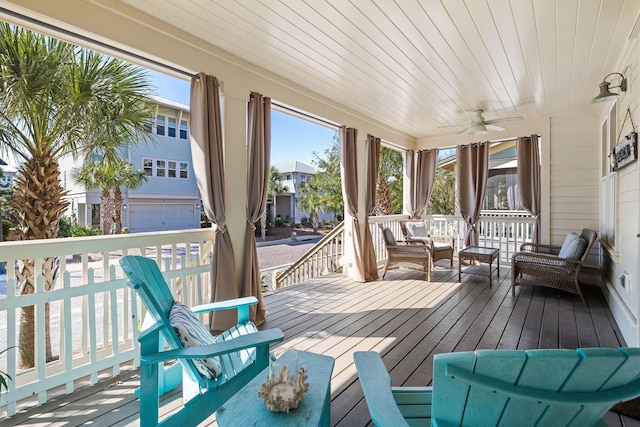 wooden terrace featuring covered porch, ceiling fan, and a garage