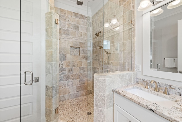 bathroom with a shower with door, vanity, and crown molding