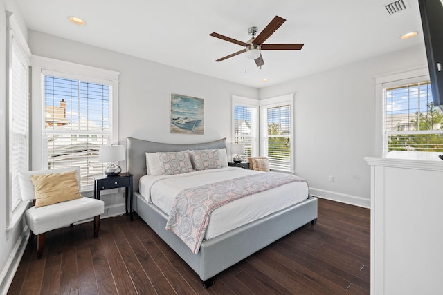 bedroom featuring dark hardwood / wood-style flooring, multiple windows, and ceiling fan