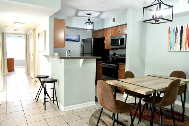 kitchen featuring a kitchen breakfast bar, hanging light fixtures, light tile patterned floors, kitchen peninsula, and stainless steel appliances