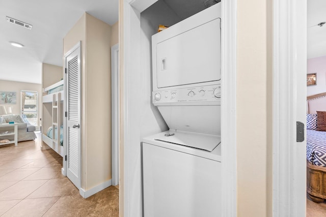 washroom featuring stacked washer / drying machine and light tile patterned floors