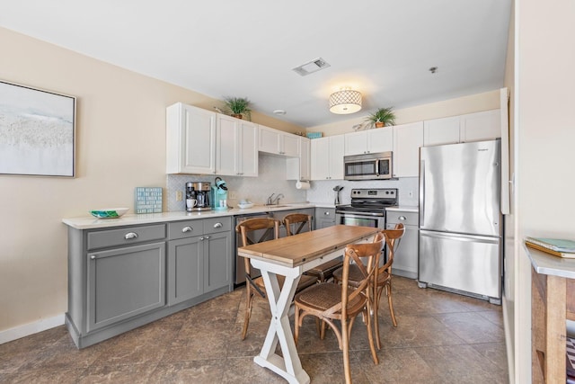 kitchen featuring backsplash, white cabinetry, sink, gray cabinetry, and stainless steel appliances