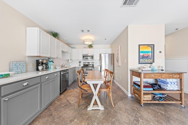 kitchen featuring backsplash, sink, white cabinets, gray cabinets, and appliances with stainless steel finishes