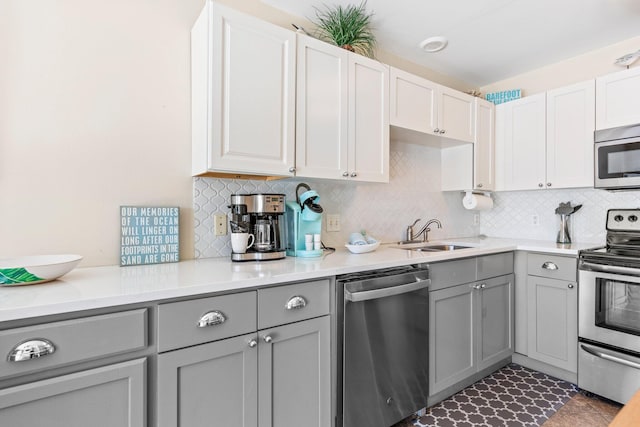 kitchen with stainless steel appliances, sink, backsplash, and gray cabinetry