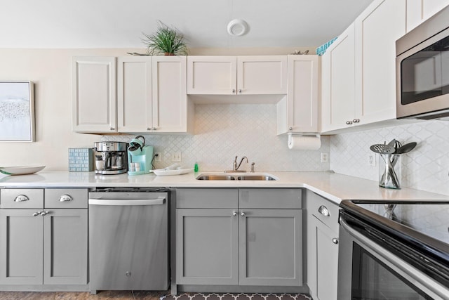 kitchen with decorative backsplash, gray cabinetry, stainless steel appliances, sink, and white cabinetry