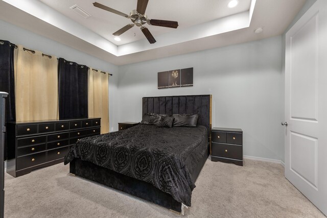 carpeted bedroom with a tray ceiling and ceiling fan