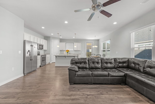 living room with hardwood / wood-style flooring and ceiling fan with notable chandelier