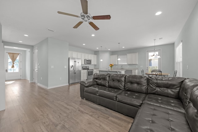 living room featuring sink, light hardwood / wood-style flooring, and ceiling fan