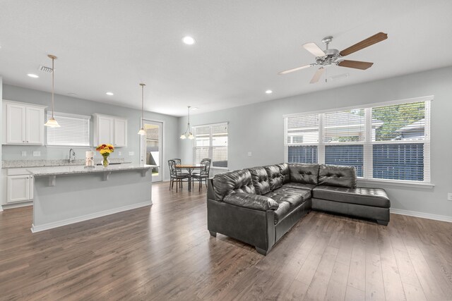 living room featuring ceiling fan with notable chandelier, sink, and dark hardwood / wood-style floors