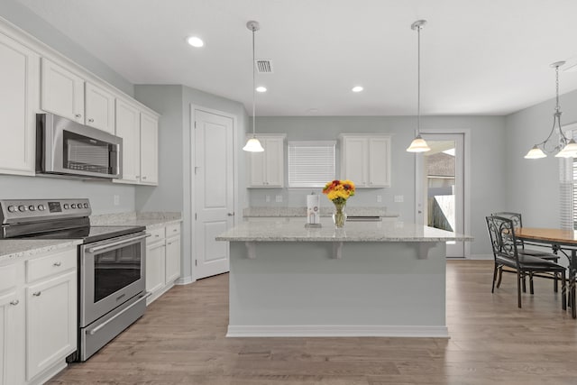 kitchen featuring appliances with stainless steel finishes, white cabinetry, a kitchen island with sink, and light hardwood / wood-style floors