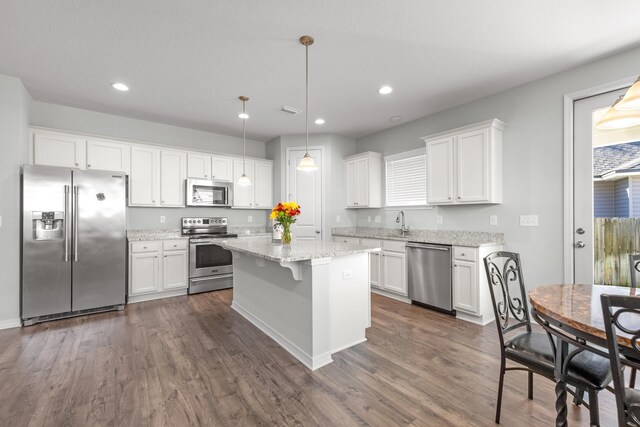 kitchen with white cabinetry, appliances with stainless steel finishes, pendant lighting, and dark wood-type flooring