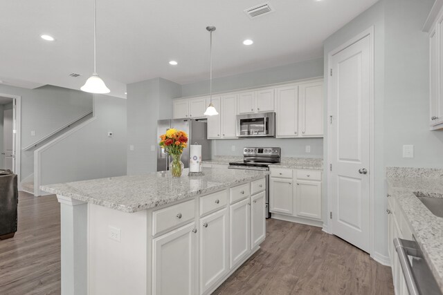 kitchen featuring white cabinets, appliances with stainless steel finishes, a center island, and hanging light fixtures