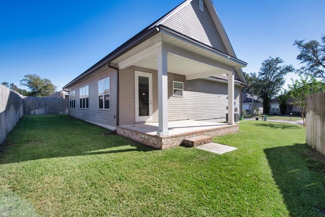 rear view of house with a patio and a lawn