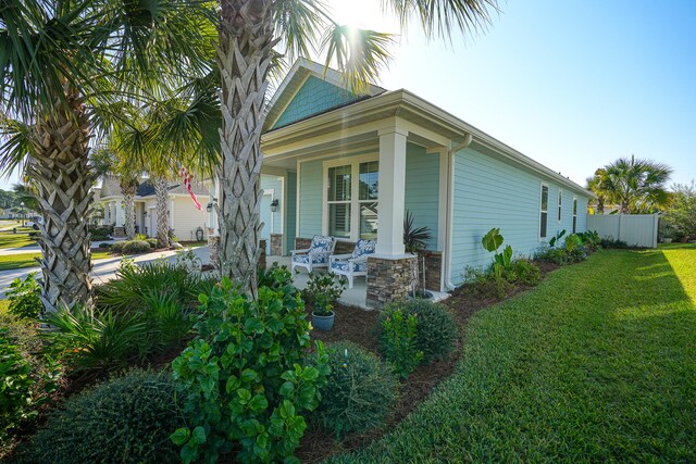 view of side of property with covered porch and a yard