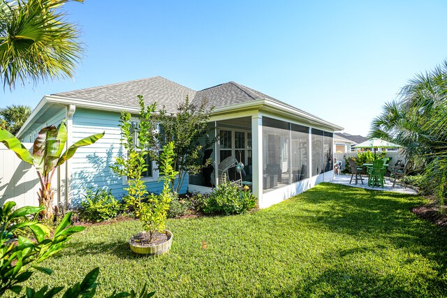 rear view of house featuring a patio area, a yard, and a sunroom