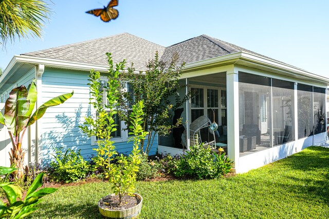 rear view of property featuring a yard and a sunroom