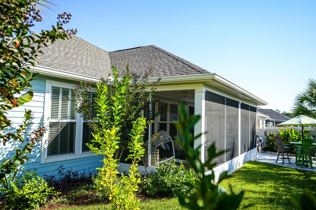 view of property exterior with a yard, a patio, and a sunroom