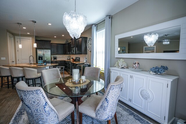 dining area featuring sink, dark hardwood / wood-style flooring, and ceiling fan with notable chandelier