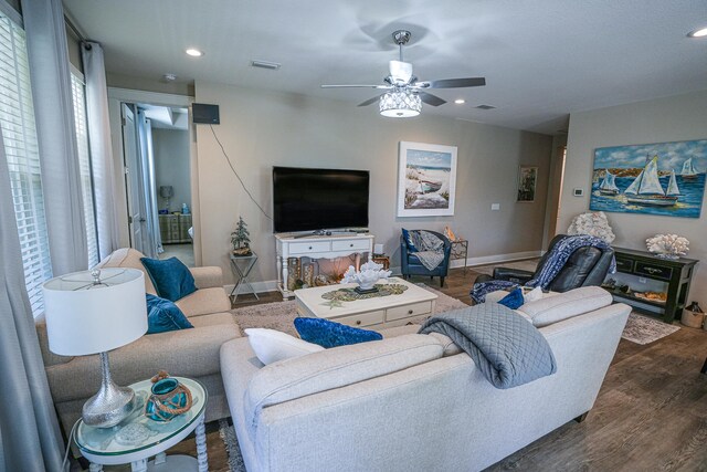 living room featuring dark wood-type flooring and ceiling fan