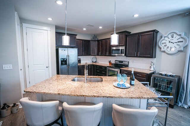 kitchen featuring a center island with sink, sink, hanging light fixtures, and stainless steel appliances