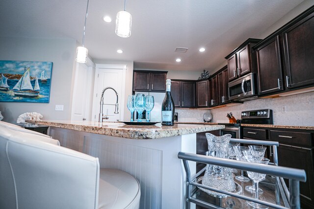 kitchen featuring backsplash, stainless steel appliances, a breakfast bar, and hanging light fixtures