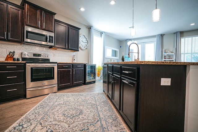 kitchen featuring appliances with stainless steel finishes, decorative backsplash, hanging light fixtures, and plenty of natural light