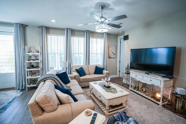 living room featuring ceiling fan, a textured ceiling, and dark hardwood / wood-style floors