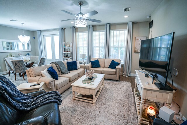 living room with wood-type flooring and ceiling fan with notable chandelier