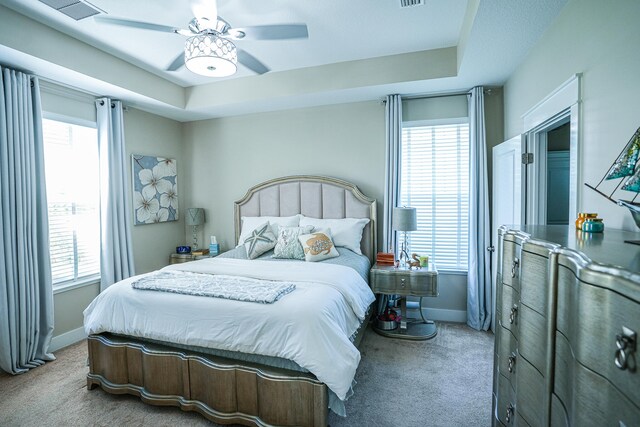 carpeted bedroom featuring a raised ceiling and ceiling fan