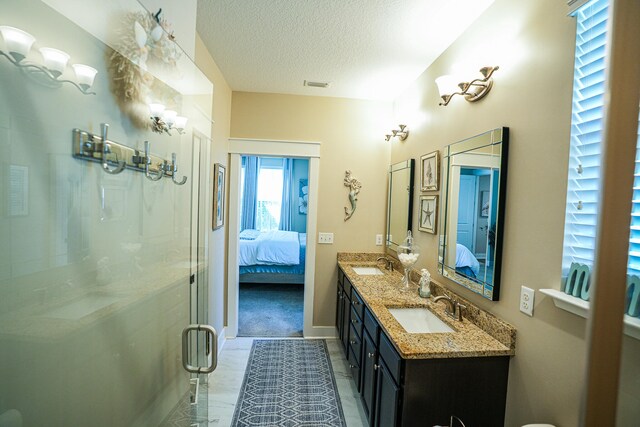 bathroom with vanity, an enclosed shower, and a textured ceiling