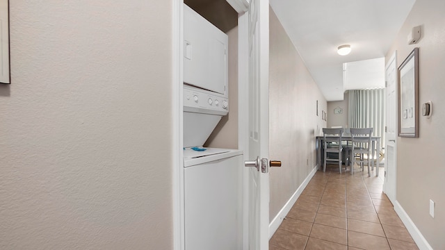 corridor featuring stacked washer / drying machine and light tile patterned flooring