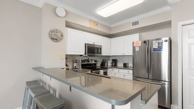 kitchen with kitchen peninsula, white cabinetry, stainless steel appliances, crown molding, and a breakfast bar