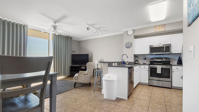 kitchen with kitchen peninsula, white cabinets, light tile patterned floors, appliances with stainless steel finishes, and ceiling fan