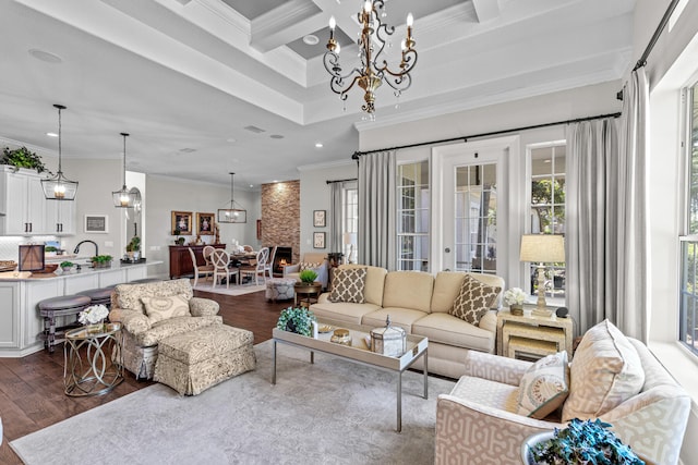 living room with coffered ceiling, dark hardwood / wood-style floors, beam ceiling, crown molding, and an inviting chandelier