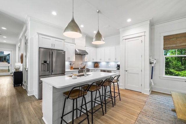 kitchen with white cabinets, high end refrigerator, backsplash, extractor fan, and light wood-type flooring