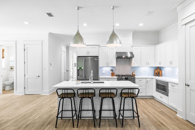 kitchen featuring extractor fan, light hardwood / wood-style flooring, stainless steel appliances, a center island with sink, and white cabinets