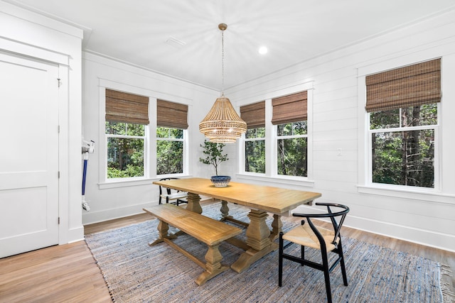 dining space with an inviting chandelier, wooden walls, and hardwood / wood-style floors