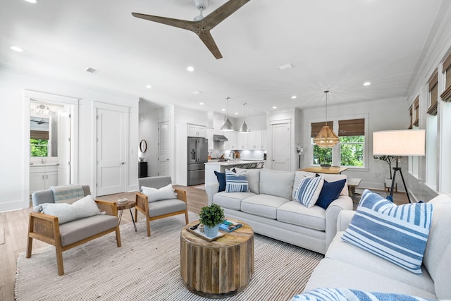 living room featuring ornamental molding, light wood-type flooring, and ceiling fan