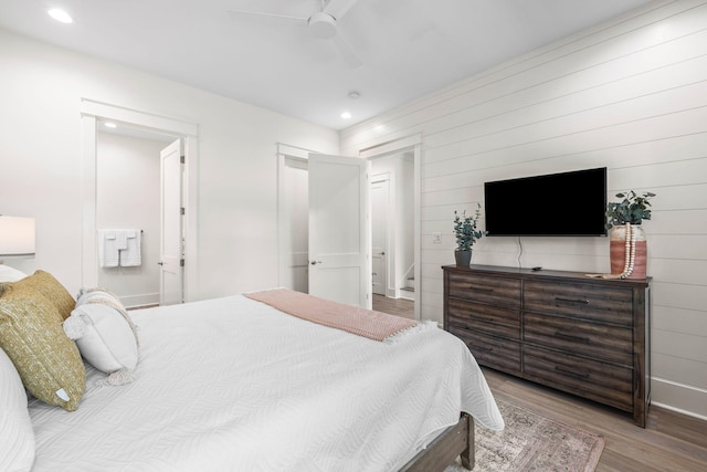 bedroom featuring connected bathroom, hardwood / wood-style floors, and ceiling fan